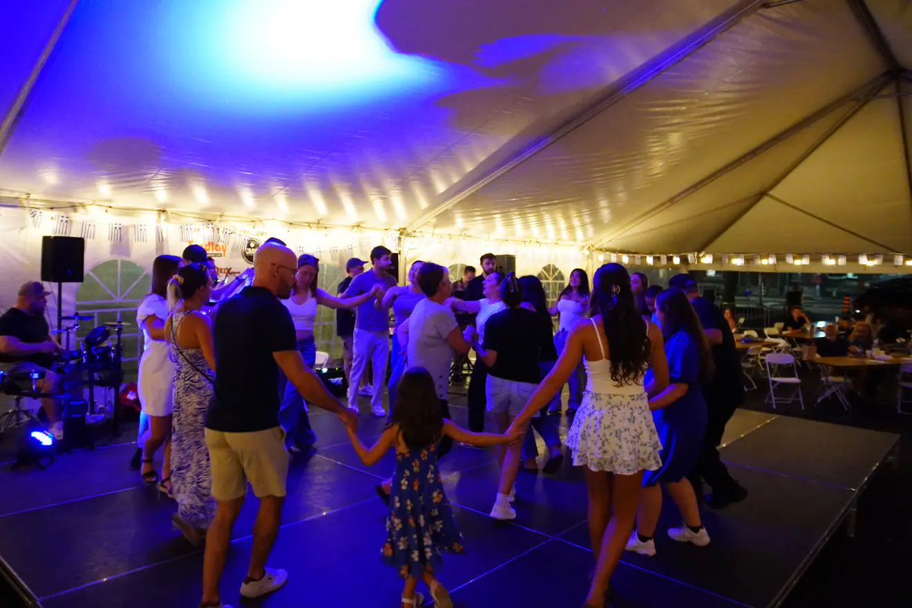 Guests joining hands in a dance circle under the tent