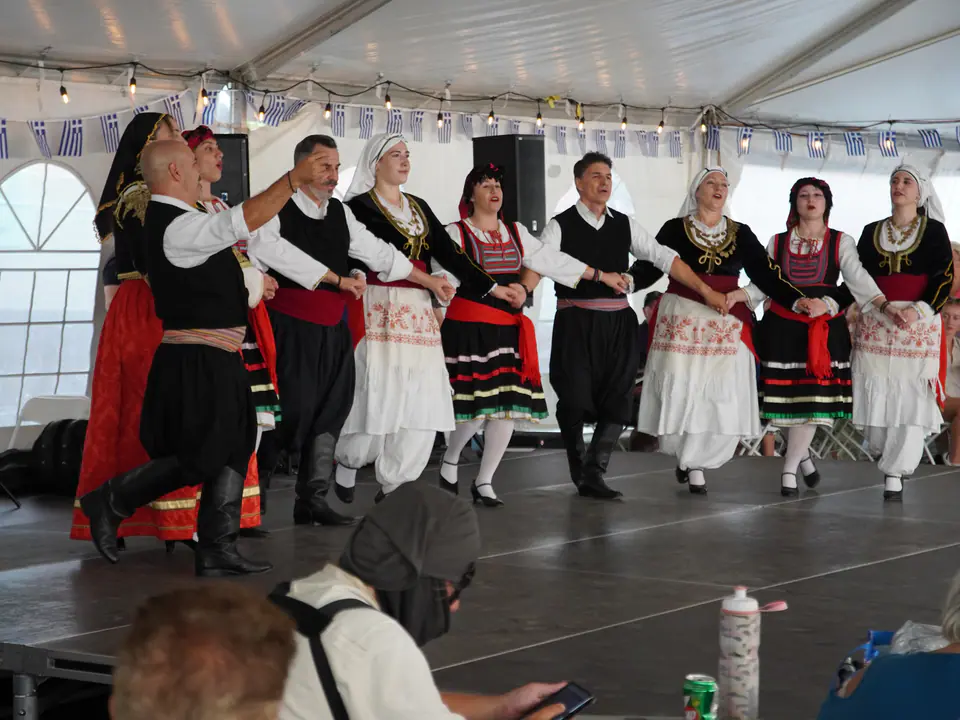 Traditional dancers linked arm in arm on stage under the festival tent